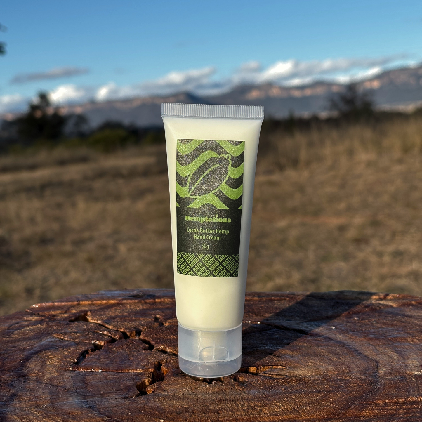 Tube of hand cream with a green label on a wooden surface with a mountainous background