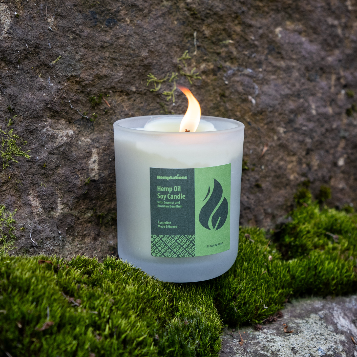 Candle with a label on a stone surface with grass