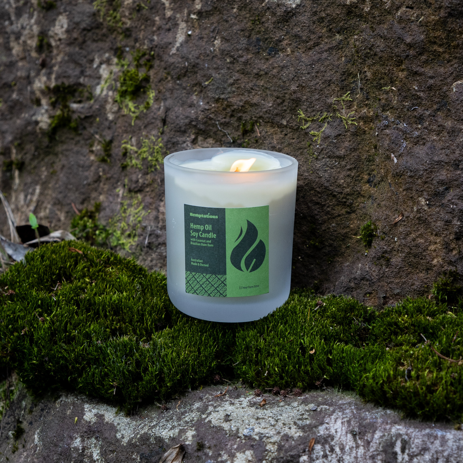 Candle with a green label on a mossy stone surface