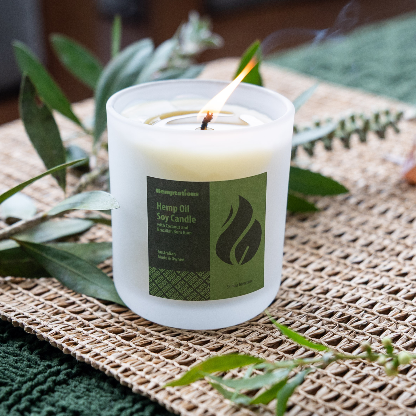 Hemp candle with a label on a woven mat with green leaves