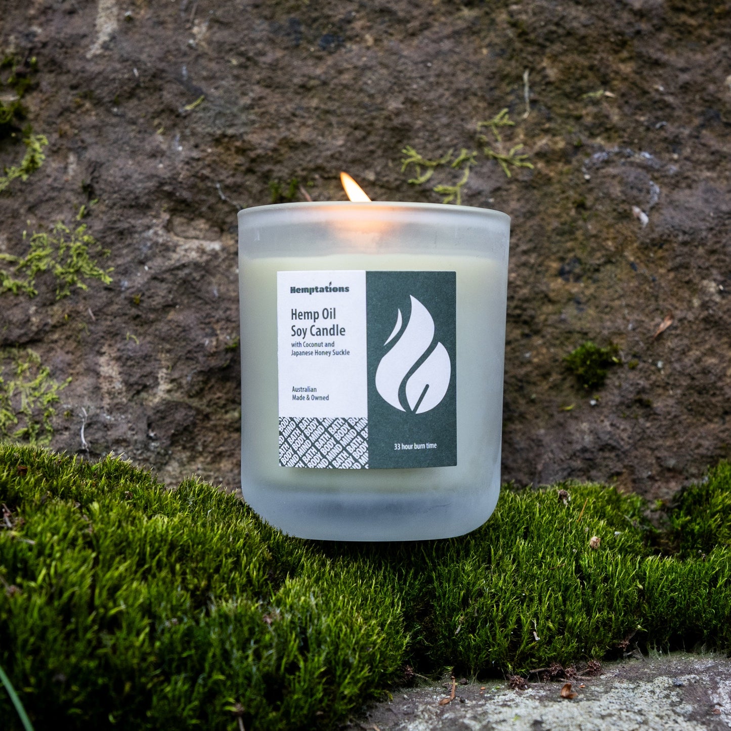 Candle with a label on a stone surface with moss