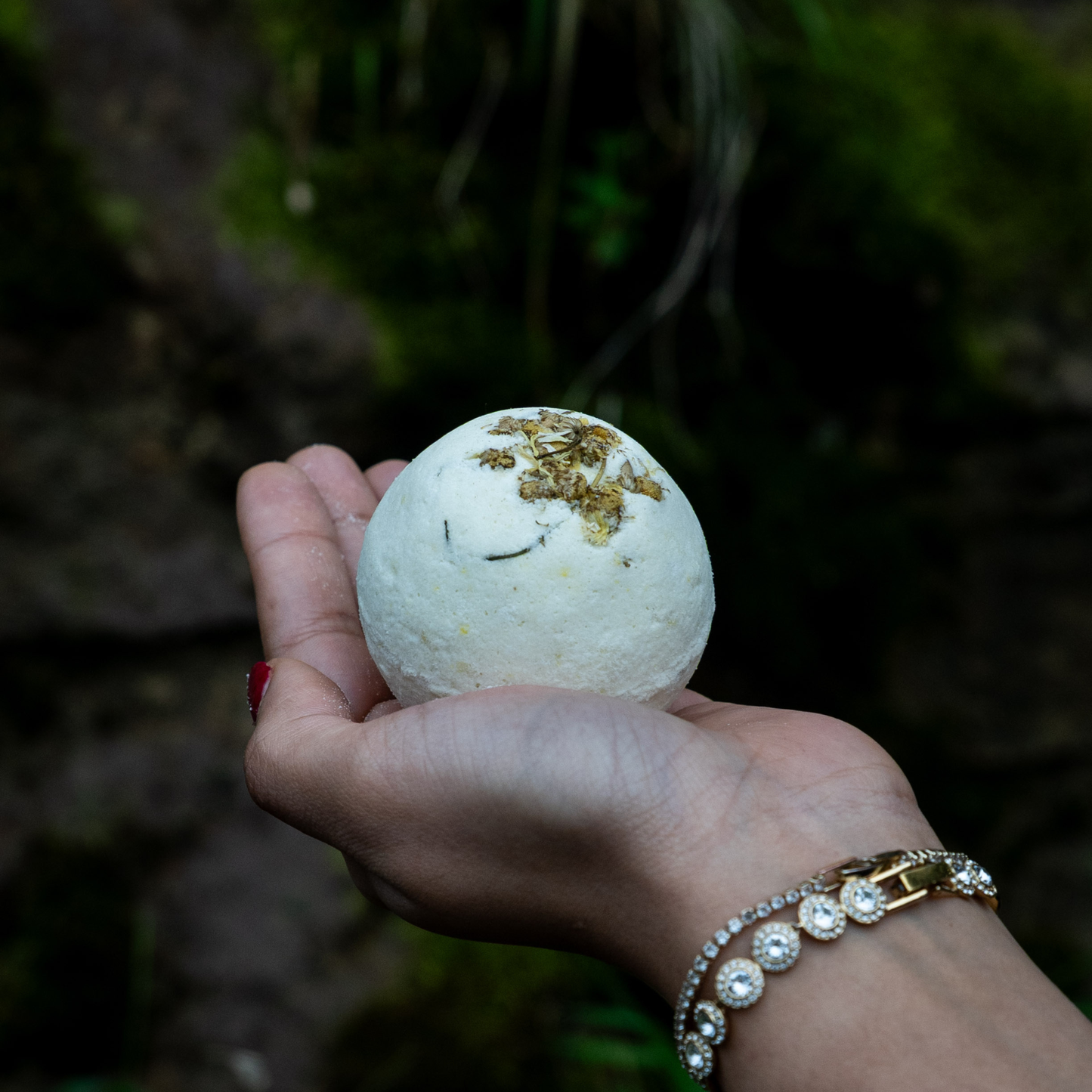 Hand holding a bath bomb with a blurred natural background