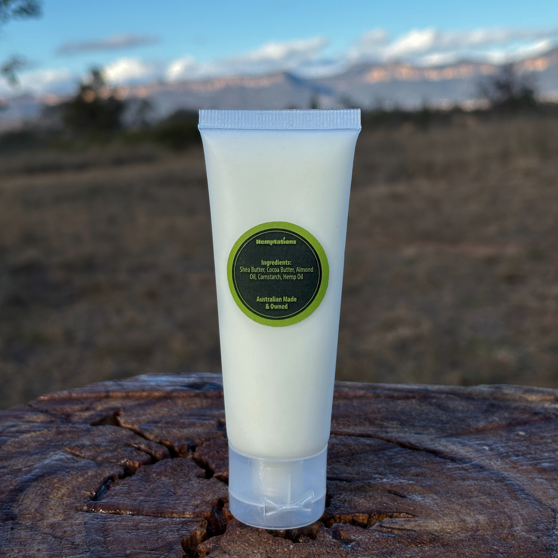 Tube of hemp handcream with a green label on a wooden surface outdoors