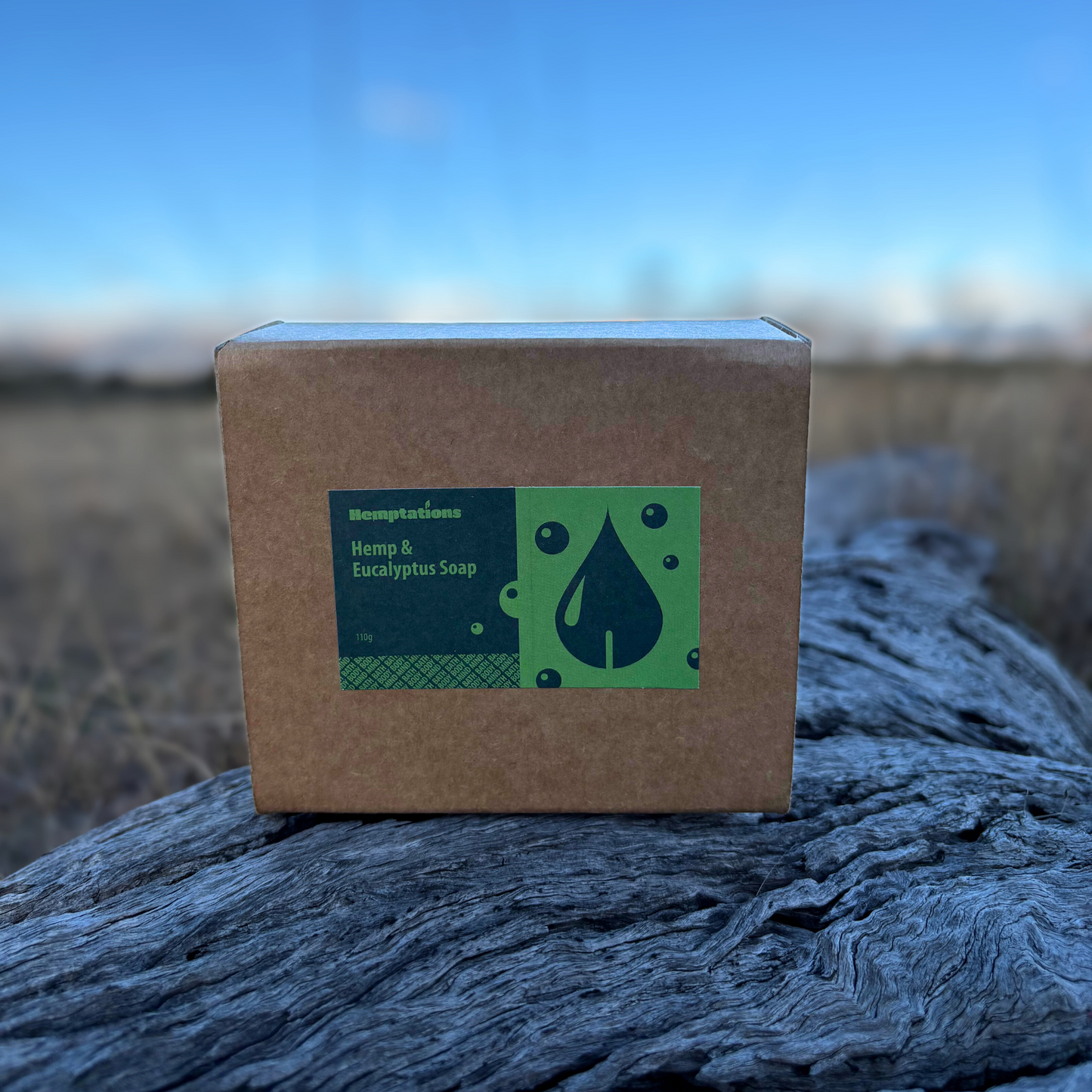 Box of Hemp & Eucalyptus Soap on a wooden log with a blurred natural background