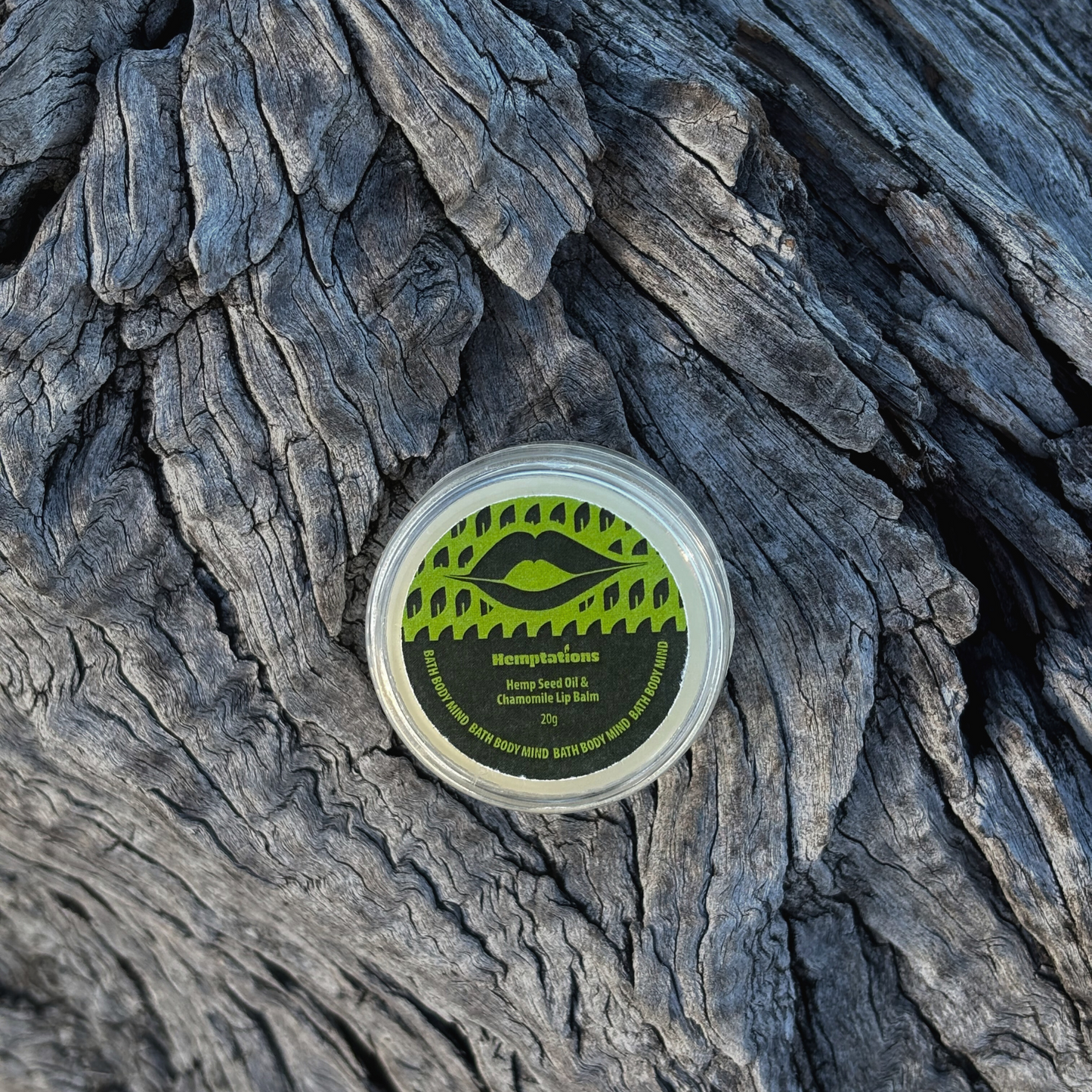 lip balm Container with a green label on a textured wooden surface